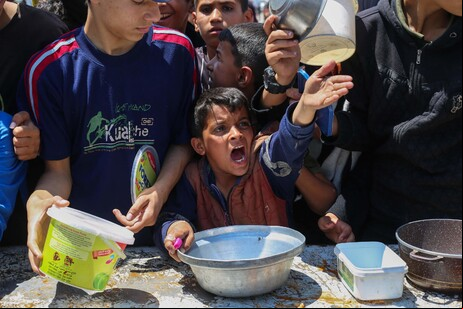 Crianças palestinas aguardam por porção de comida em campo de refugiados na Faixa de Gaza